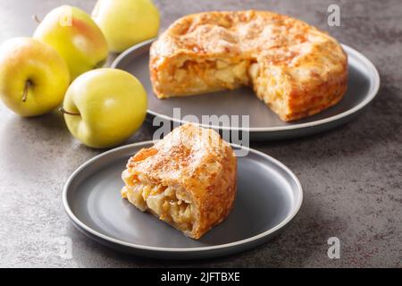 Torta di mele con crosta di formaggio primo piano nel piatto sul tavolo. Orizzontale Foto Stock