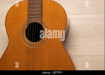 Corpo di chitarra classica in primo piano, su sfondo di legno chiaro con spazio di copia. Foto Stock