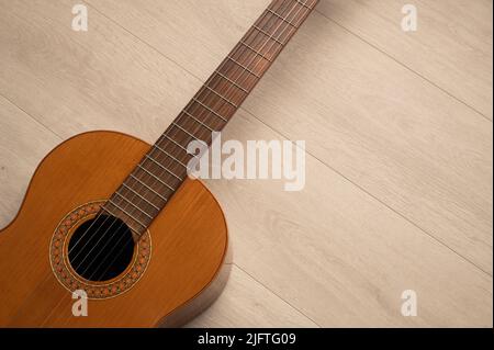 Corpo di chitarra classica in primo piano, su sfondo di legno chiaro con spazio di copia. Foto Stock