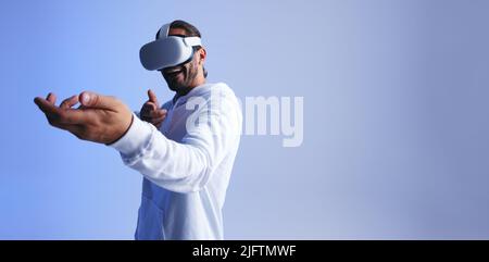 Ragazzo allegro che spara con le mani in un gioco di realtà virtuale. Un giovane felice sorridente indossando una cuffia per realtà virtuale. Giovane havin Foto Stock