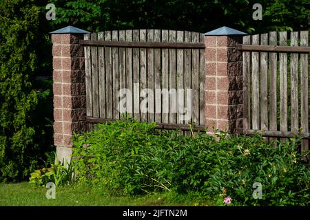 Due pannelli di una classica recinzione in legno di piume da giardino con montanti di supporto in calcestruzzo Foto Stock