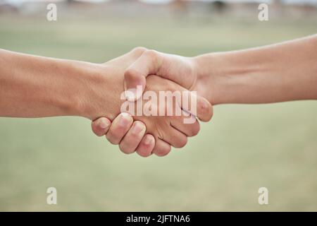 Primo piano di due giocatori di baseball sconosciuti che scuotono le mani mentre si trova su un campo di erba. Due sportivi salutano o si congratulano per un buon gioco Foto Stock