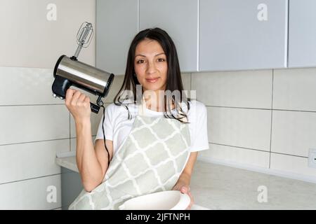 Confettatrice femminile che lavora con il miscelatore. Fasi del processo di cottura. Foto Stock