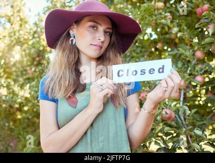 Ritratto di una donna che ha chiuso il cartello per pubblicizzare la fine della stagione di raccolta di mele in frutteto fattoria. L'agricoltore chiude l'attività agricola a causa di Foto Stock