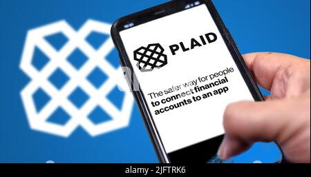 San Francisco, USA, giugno 2022: Tenere un telefono con la home page di Plaid sullo schermo. Logo plaid sfocato su sfondo blu. Plaid è un servizio finanziario Foto Stock
