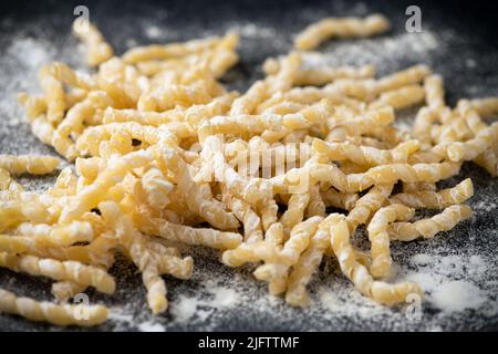 La pasta cruda viene fatta in busiate su tavola di legno da vicino. Sicilia Trapani bontà Foto Stock