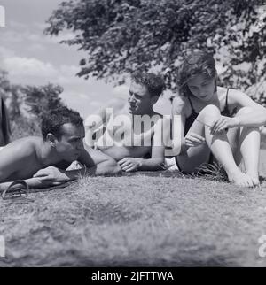 Foto d'epoca di tre ragazzi in età universitaria che si rilassano in estate in un parco alla fine dei 1940s amici seduti sul prato centrale New York state USA Foto Stock