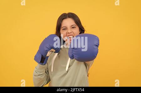 punzonatura bambino aggressiva in guanti da boxe su sfondo giallo, sport Foto Stock