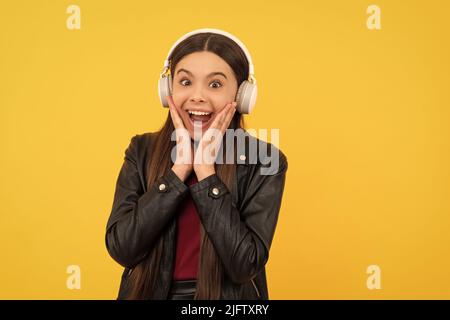 stupito bambino in cuffie su sfondo giallo, musica Foto Stock