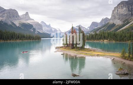 Isola degli alberi nel mezzo del lago alpino turchese circondato da montagne, con kayak, Canada Foto Stock