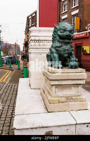 Una statua del leone accanto a Chinatown Gate, Nelson Street. Chinatown è un'area di Liverpool che è un'enclave etnica che ospita la più antica comunità cinese Foto Stock