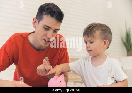 padre e figlio che mettono le monete nella banca del piggy, colpo medio, concetto finanziario. Foto di alta qualità Foto Stock