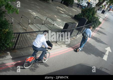 Visto da una vista aerea è ciclista a cavallo di una bicicletta Santander a noleggio e seguendo il pilota di un eScooter, entrambi non indossando caschi giù Piccadilly a Westminster, il 5th luglio 2022, a Londra, Inghilterra. Foto Stock