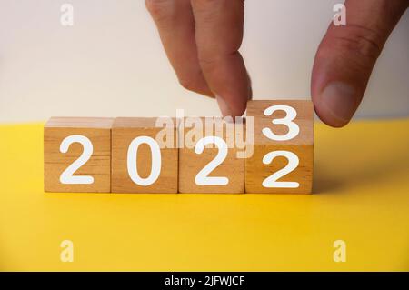 2023 felice anno nuovo simbolo. Mano che gira un cubo da 2022 a 2023. Spazio di copia. 2023 felice anno nuovo concetto. Foto Stock