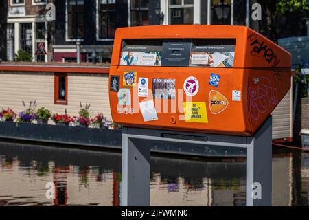 Amsterdam, Paesi Bassi - 23 giugno 2022: Postbox rosso lungo il canale Foto Stock
