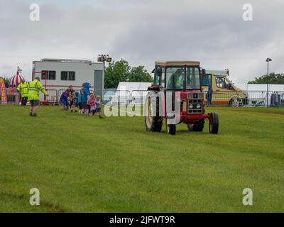 Tug di guerra tra i bambini e un trattore d'epoca al Launceston Steam & Vintage Rally, Cornovaglia, Regno Unito Foto Stock