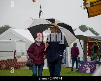 Coppia nella pioggia al Launceston Steam & Vintage Rally, Cornovaglia, Regno Unito Foto Stock