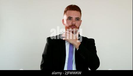 Direttore esecutivo in stile irlandese che tocca il pensiero della barba, uomo redhair che tocca il viso Foto Stock