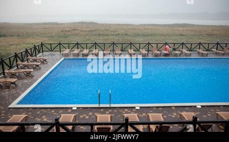 La pioggia incredibilmente pesante e il vento veloce e duro rovinano il caldo e soleggiato clima estivo nella base tranquilla con piscina per una vacanza attesa a lungo Foto Stock