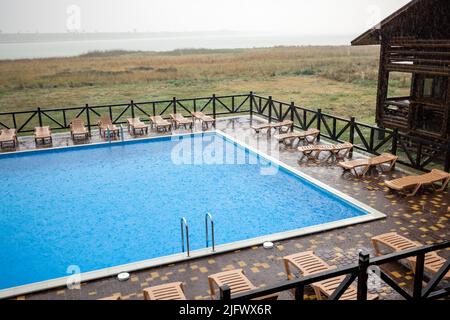 La pioggia incredibilmente pesante e il vento veloce e duro rovinano il caldo e soleggiato clima estivo nella base tranquilla con piscina per una vacanza attesa a lungo Foto Stock