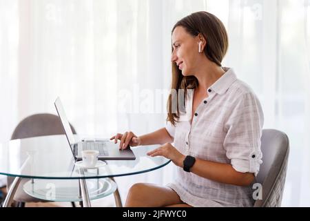 Giovane donna che lavora online con un notebook a casa Foto Stock