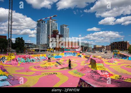 Il Suvilahti DIY Skatepark rosa e giallo con il centro commerciale Redi e gli alti edifici Kalasatama sullo sfondo a Helsinki, Finlandia Foto Stock