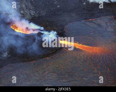 Una prospettiva telefotografica della bocca ovest nella bocca ovest che fornisce la lava al lago di lava in Halema'uma'u, alla cima K?lauea, Hawaii. La lava stagionata all'interno del cono spruzzi fornisce la lava nel lago di lava attraverso il canale di fuoriuscita. Il flusso di lava in rapido movimento è incandescente quando entra nel lago di lava alla base del cono. Quando la lava rallenta e si raffredda, una sottile crosta inizia a formarsi sulla superficie (centro a destra). Questa foto è stata scattata dal bordo del cratere meridionale il 3 novembre. Credit N. Deligne/USGS Foto Stock