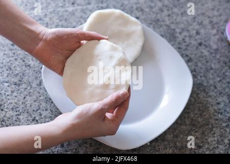 Donna mani che fanno arepas in cucina. Cibo latino. Foto Stock