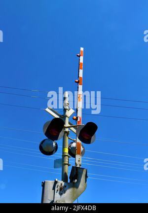 Un colpo verticale di una ferrovia che attraversa la luce con il cielo blu sullo sfondo Foto Stock