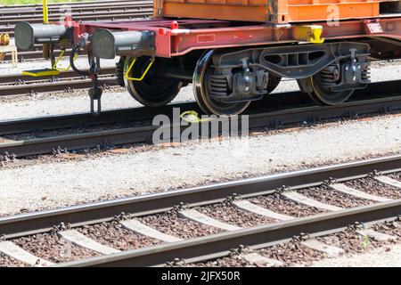 Vista parziale del lato anteriore con paracolpi di un carro container a pianale ribassato su binari ferroviari in una giornata di sole come concetto per il trasporto merci e ca Foto Stock