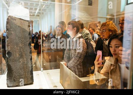 I visitatori guardano la pietra Rosseta. La pietra Rosetta è una stele grandidiorite inscritta con tre versioni di un decreto emesso a Memphis, in Egitto. Il Foto Stock