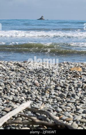 Roccia off-shore oltre la spiaggia di pietra Rapahoe e vista all'orizzonte con promontorio e onde di surf, Reefton, South Island New Z1ealand. Foto Stock