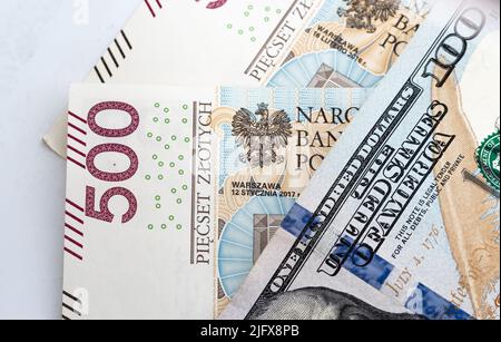 Banconote in denaro, banconote in dollari statunitensi e zloty polacche sparse su sfondo bianco. Tassi di cambio da PLN a USD. Versamento di denaro. Foto Stock