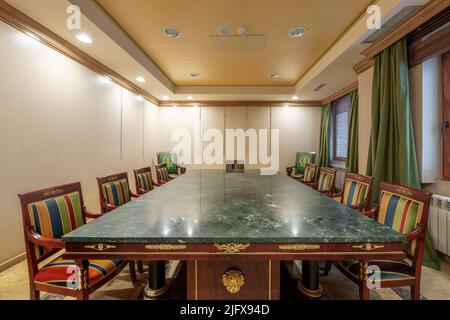 Sala riunioni con tavolo in legno e marmo verde con sedie rivestite in tessuti colorati Foto Stock