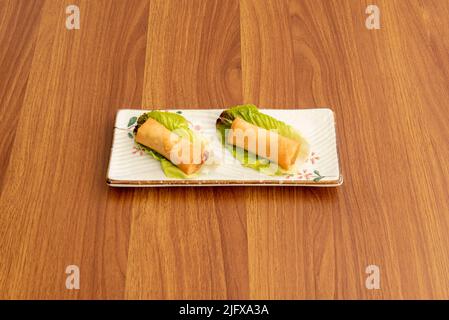 Piccoli involtini primaverili asiatici farciti di verdure sulle foglie di lattuga Foto Stock