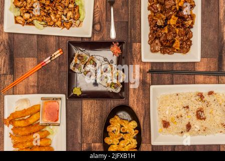 Set di piatti orientali con gamberi in pastella con panko, wonton fritto, riso al prosciutto, rotolo di riso al tonno rosso e manzo con bambù e funghi, salsa di soia e sw Foto Stock