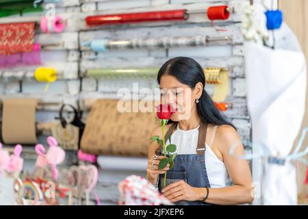 donna nel suo negozio di fiori con un bel fiore Foto Stock