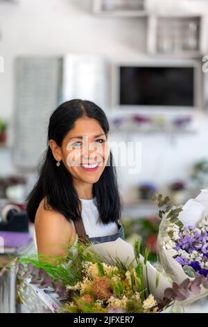 donna felice nel suo negozio di fiori Foto Stock