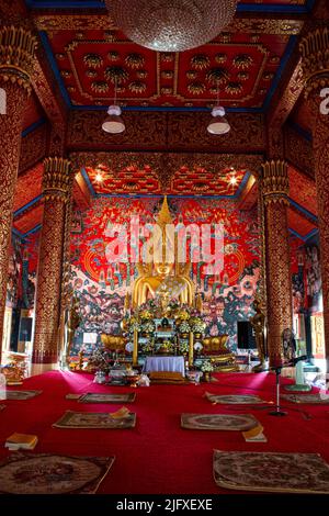 Il Buddha dorato seduto è principale in una chiesa a Wat Phra che Choeng Chum Worawihan è un luogo sacro importante della città. Fin dai tempi antichi. Foto Stock