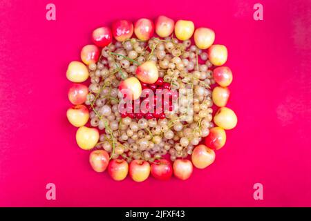 Ribes giallo e rosso con ciliegie gialle su sfondo rosa Foto Stock
