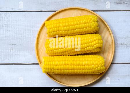 mais dolce cotto su sfondo piatto di legno, pannocchie di mais mature al vapore o corn bollito per cibo vegan cena o spuntino - vista dall'alto Foto Stock