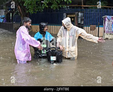 Mumbai, India. 05th luglio 2022. La gente aiuta un uomo di consegna di cibo ad attraversare una strada allagata in mezzo alle forti piogge a Mumbai. Mumbai ha assistito a forti piogge a causa delle quali le strade sono state registrate nelle aree basse e il traffico è stato lento in movimento attraverso la città. Il Dipartimento meteorologico indiano (IMD) ha previsto piogge da moderate a pesanti nelle prossime 24 ore della città. Credit: SOPA Images Limited/Alamy Live News Foto Stock