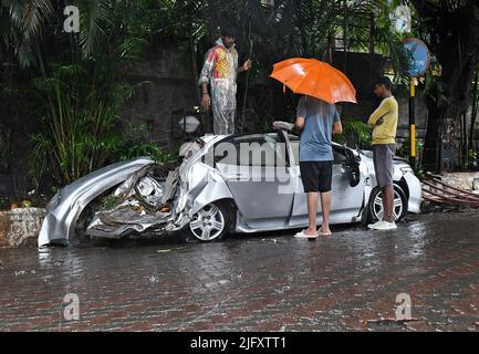 Mumbai, India. 05th luglio 2022. La gente controlla un'auto danneggiata a causa di un crollo del muro dell'edificio a Mumbai, sotto la pioggia battente. Mumbai ha assistito a forti piogge a causa delle quali le strade sono state registrate nelle aree basse e il traffico è stato lento in movimento attraverso la città. Il Dipartimento meteorologico indiano (IMD) ha previsto piogge da moderate a pesanti nelle prossime 24 ore della città. (Foto di Ashish Vaishnav/SOPA Images/Sipa USA) Credit: Sipa USA/Alamy Live News Foto Stock