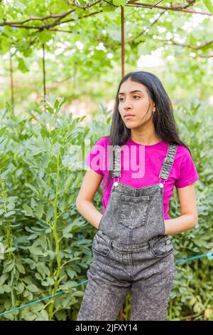 Giovane donna venezuelana latina giardinaggio e raccolta in ritratto giardino urbano Foto Stock