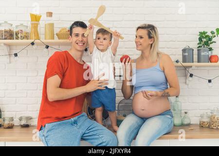 Giovane coppia caucasica con un bambino che si diverte in cucina, famiglia felice. Foto di alta qualità Foto Stock