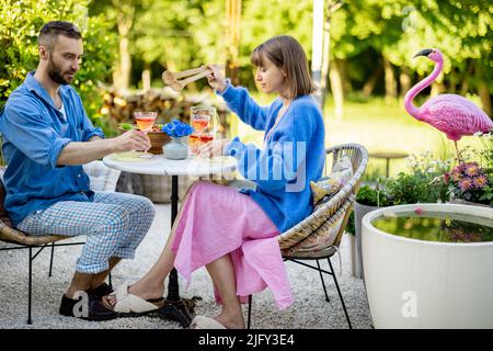 Una giovane famiglia che pranza nel cortile in un pomeriggio estivo Foto Stock