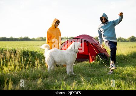 Le giovani coppie giocano con il loro cane al campeggio Foto Stock