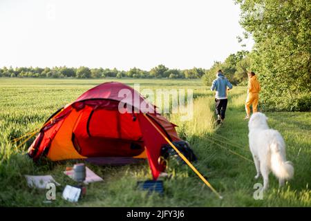 Le giovani coppie giocano con il loro cane al campeggio Foto Stock
