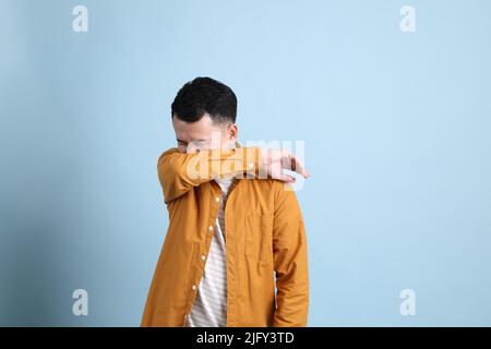 L'uomo asiatico LGBTQ con camicia gialla in piedi su sfondo blu. Foto Stock