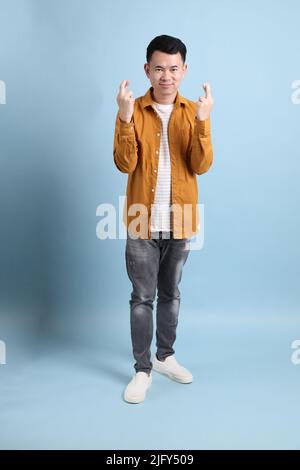 L'uomo asiatico LGBTQ con camicia gialla in piedi su sfondo blu. Foto Stock